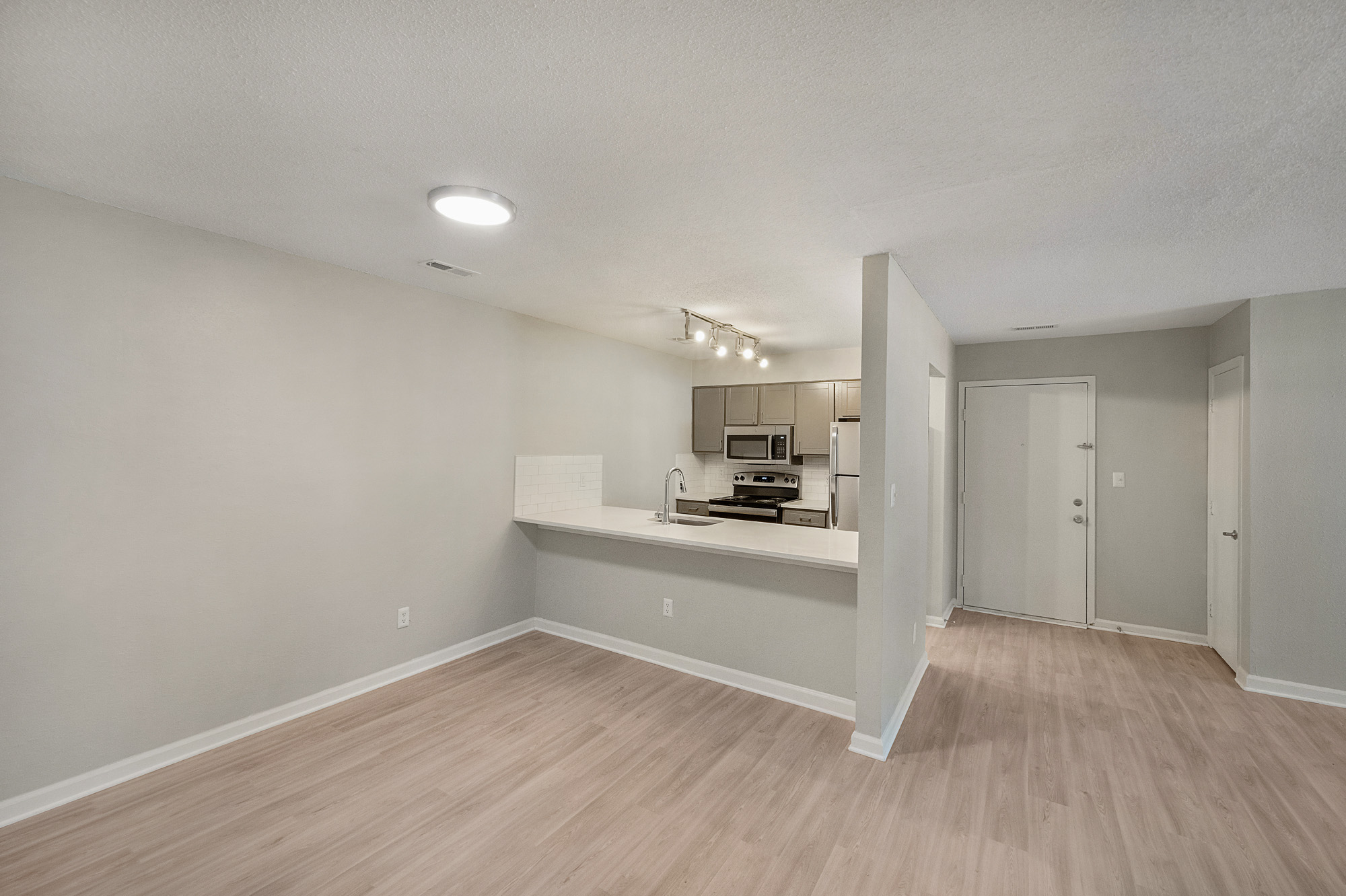 an empty room with hardwood floors and a white kitchen at The  Sawyer