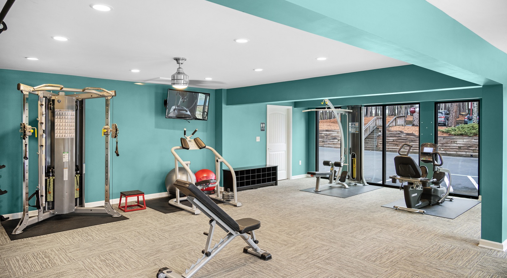 a gym room with a treadmill, weights and a television at The  Sawyer