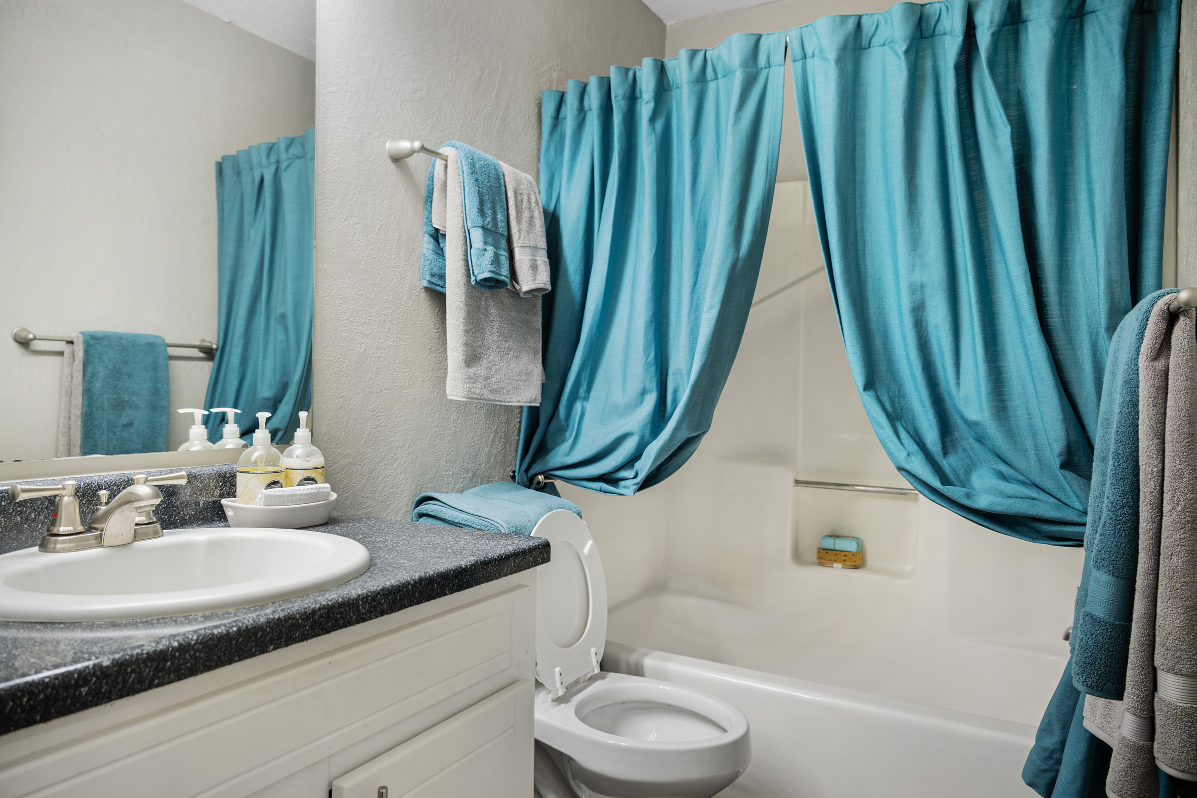 a bathroom with blue curtains and a white tub at The  Sawyer