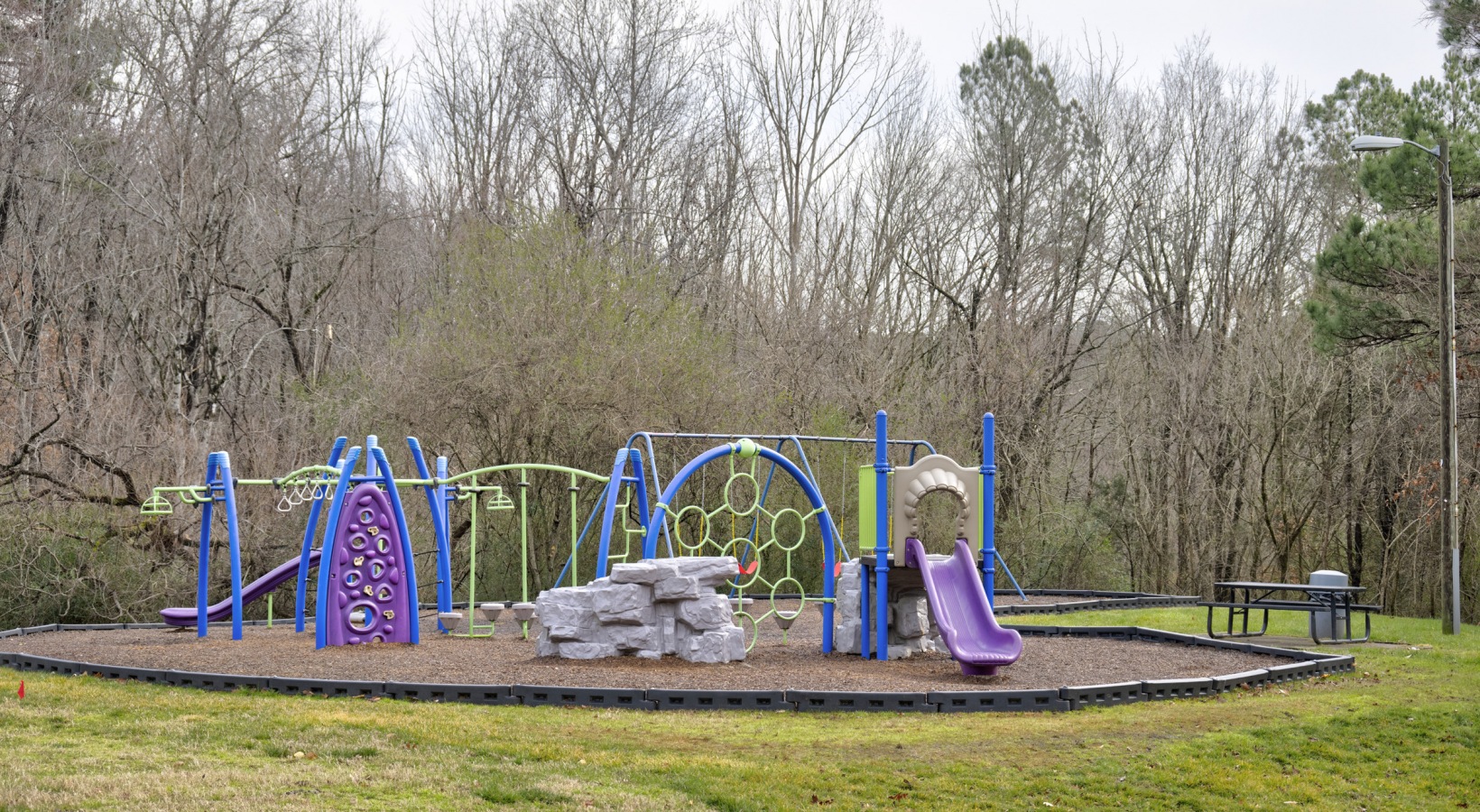 a playground with a blue slide and purple poles at The Sawyer
