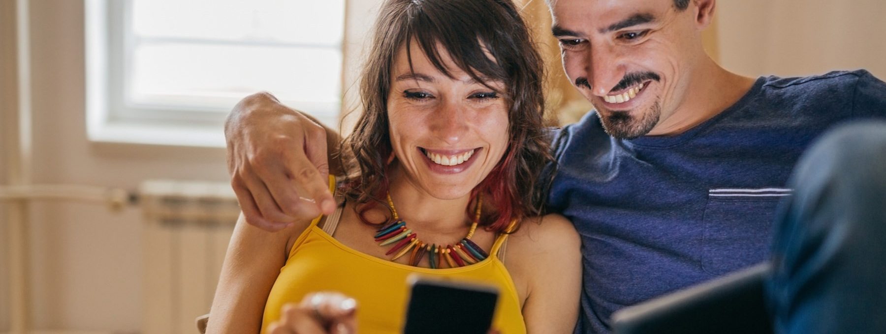a man and woman smiling while looking at a cell phone at The  Sawyer